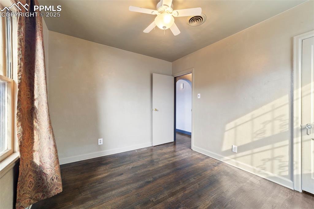 Unfurnished room featuring dark wood-style flooring and a ceiling fan