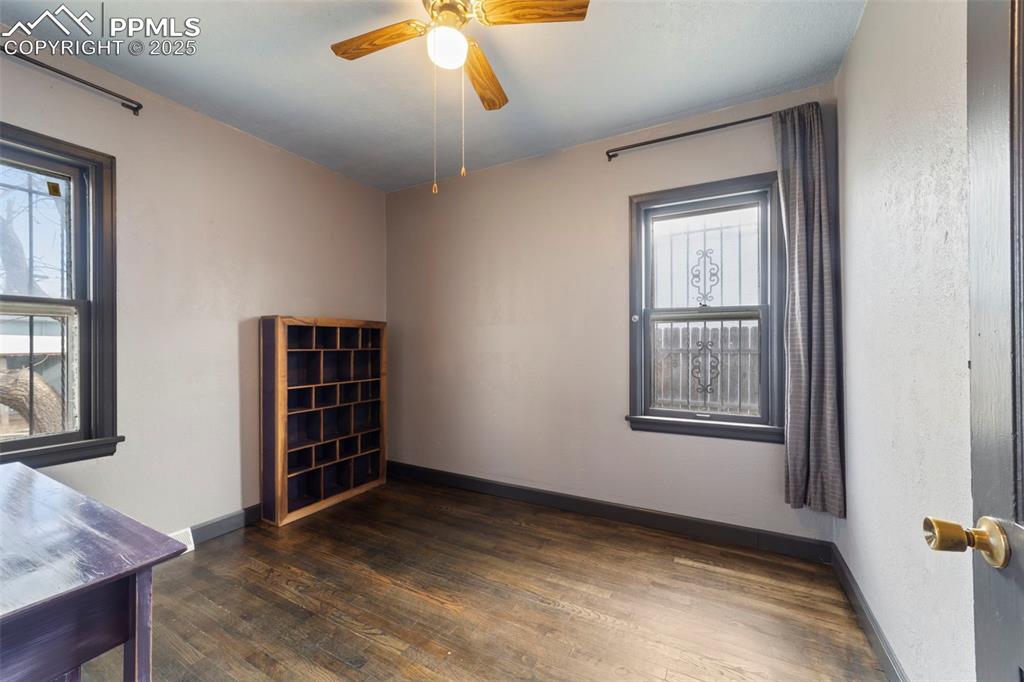 Empty room featuring dark wood-type flooring and ceiling fan