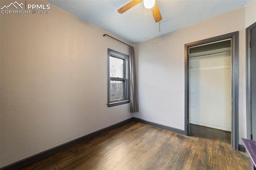 Unfurnished bedroom featuring dark wood-style flooring, a closet, and a ceiling fan