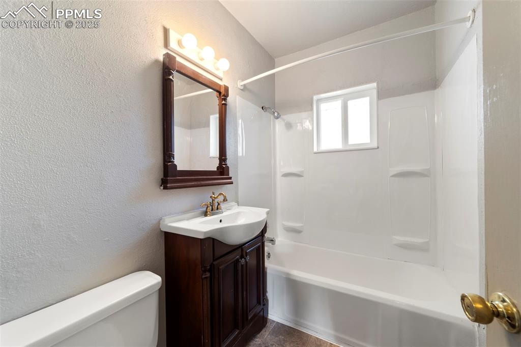 Bathroom featuring a textured wall, vanity, and bathing tub / shower combination