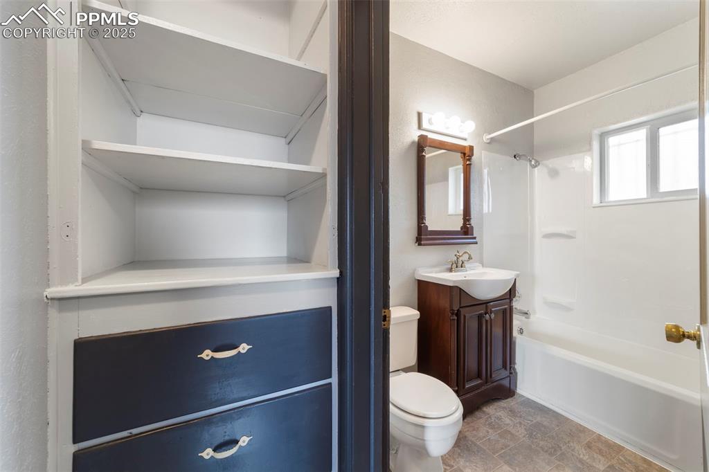 Full bathroom with vanity, bathtub / shower combination, stone finish floors, and a closet