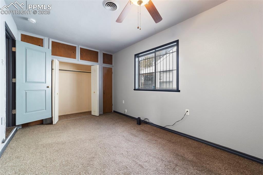 Unfurnished bedroom with carpet, a ceiling fan, and multiple closets