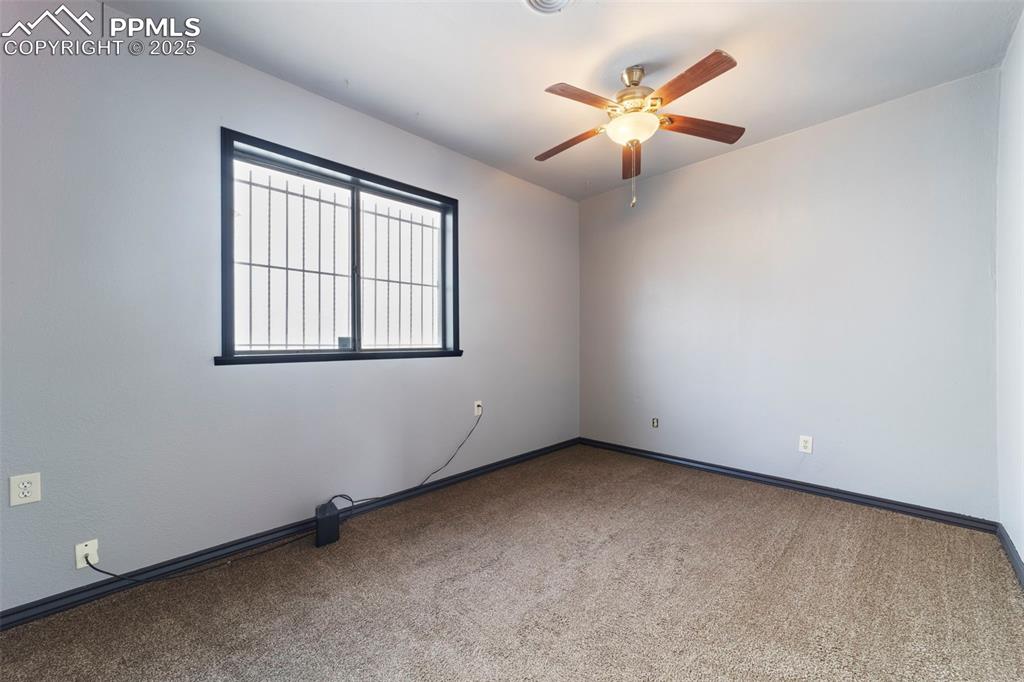 Carpeted spare room with baseboards and ceiling fan