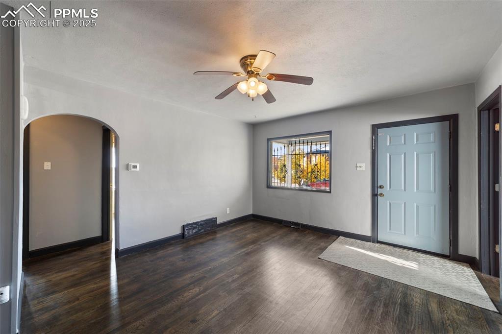 Foyer entrance featuring dark wood-style floors, arched walkways, a ceiling fan, and a textured ceiling