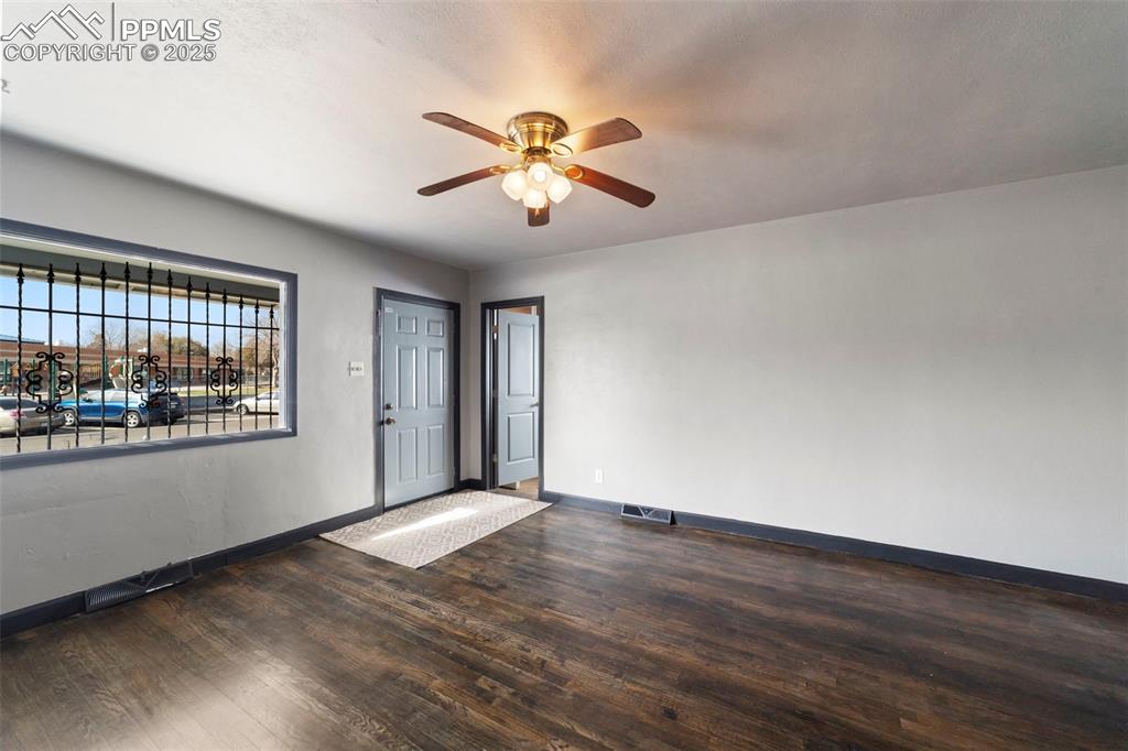 Empty room with dark wood-style flooring and a ceiling fan
