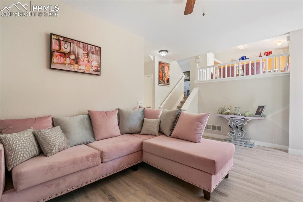 Living room featuring wood finished floors, a ceiling fan, and stairway