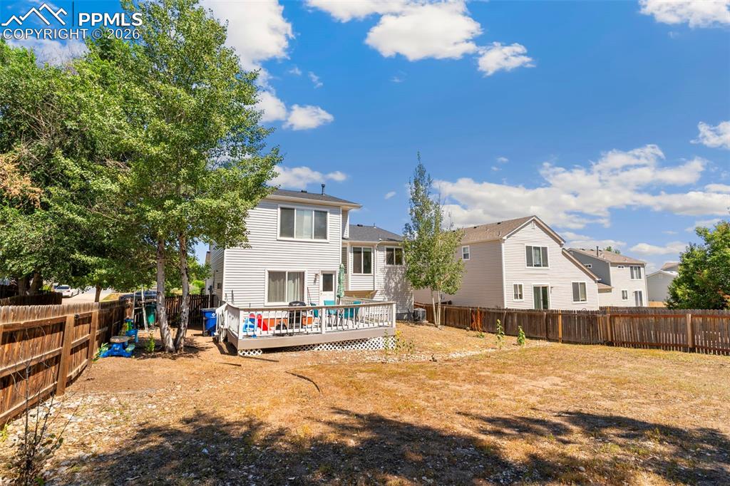 Rear view of house with a fenced backyard, a deck, and a residential view