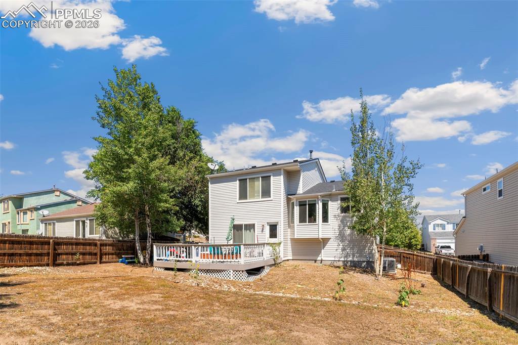 Rear view of house with a wooden deck, a fenced backyard, and a residential view