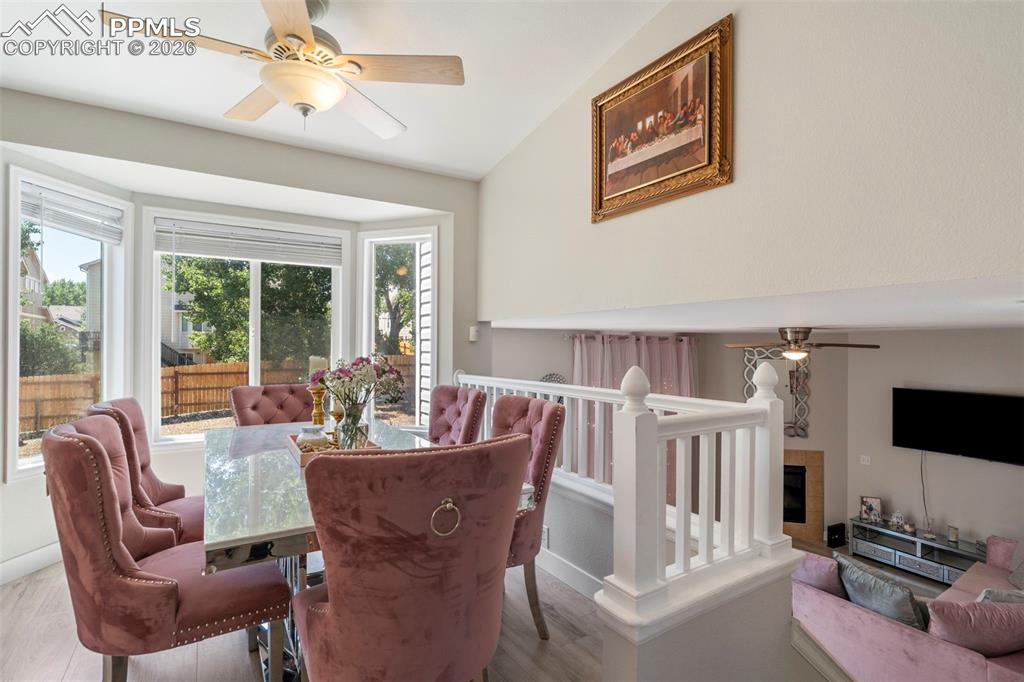 Dining room with ceiling fan, wood finished floors, and a tile fireplace