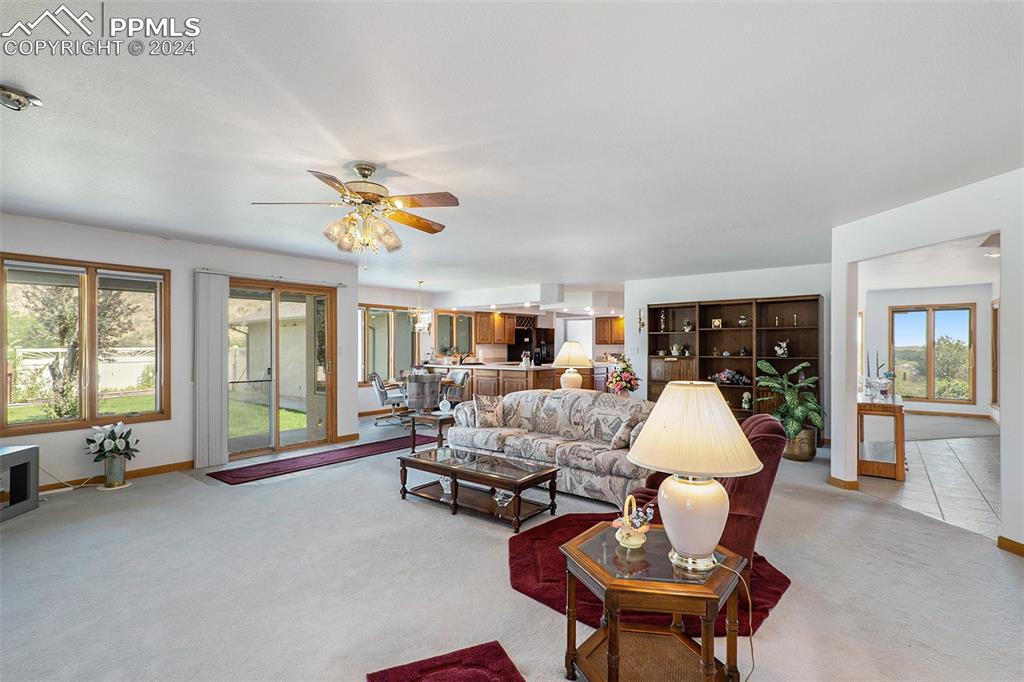 Carpeted living room featuring ceiling fan