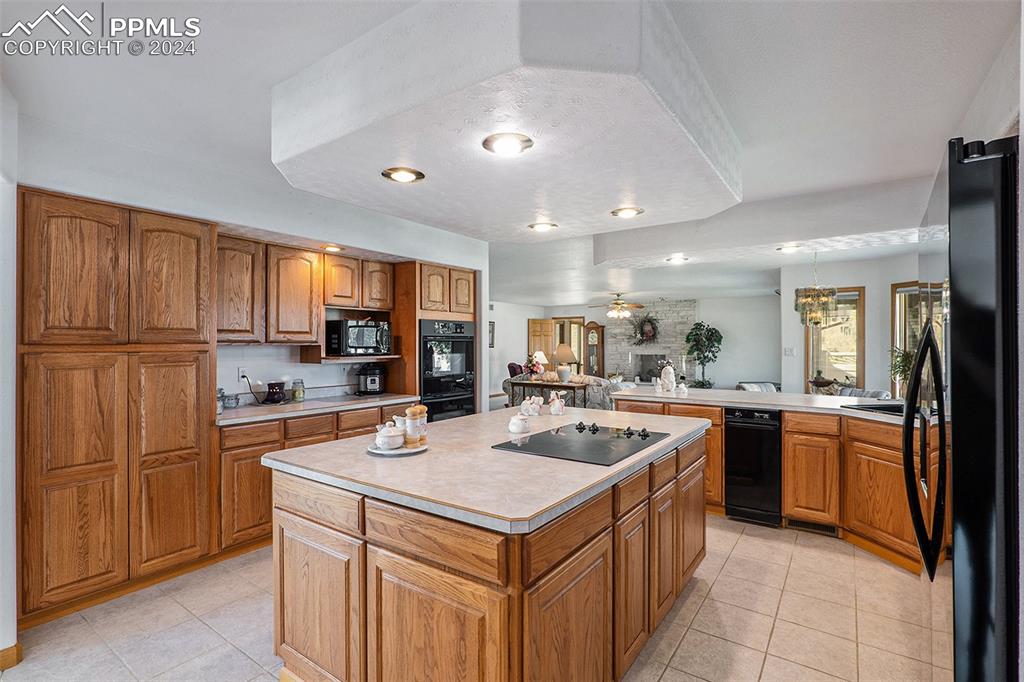 Kitchen with a center island, light tile flooring, appliances, and hanging light fixtures