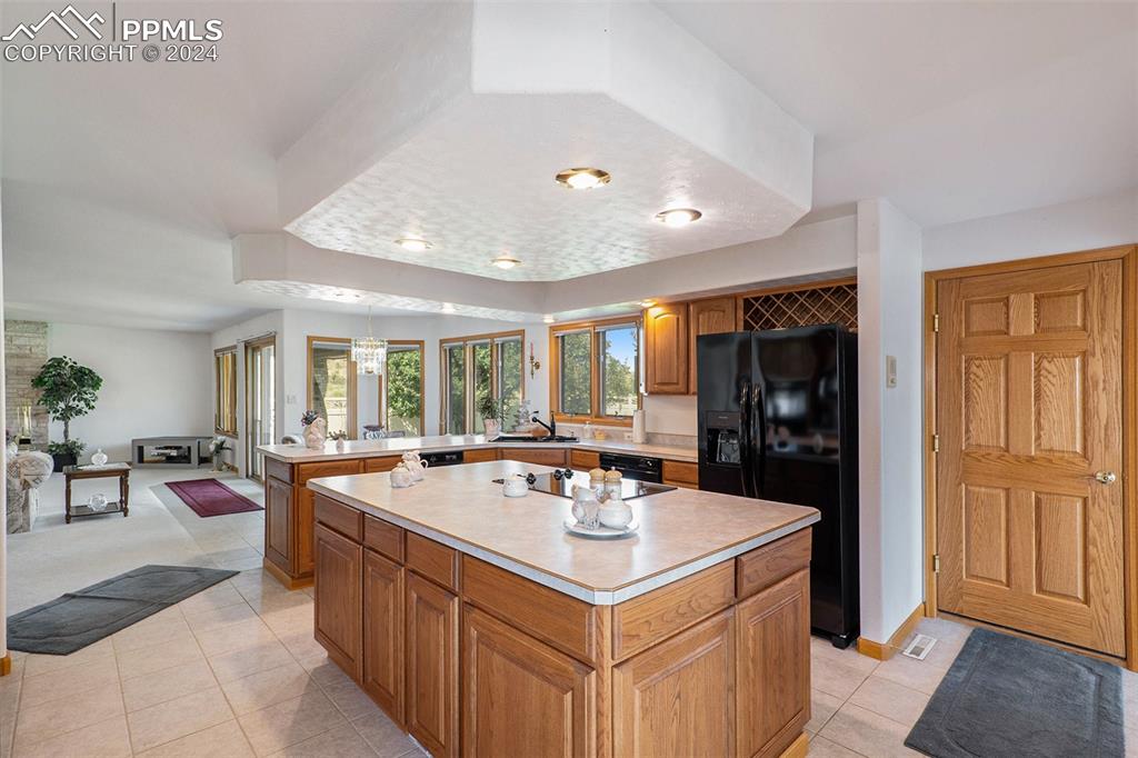 Kitchen featuring pendant lighting, sink, fridge with ice dispenser, dishwashing machine, and a center island