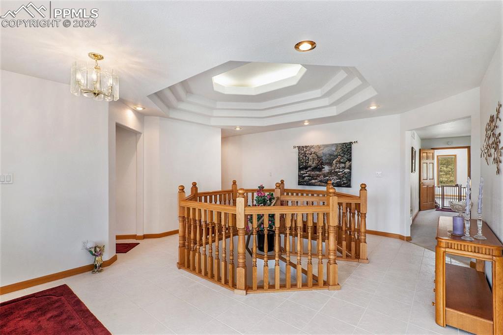 Dining room featuring a chandelier, a raised ceiling, and light tile floors