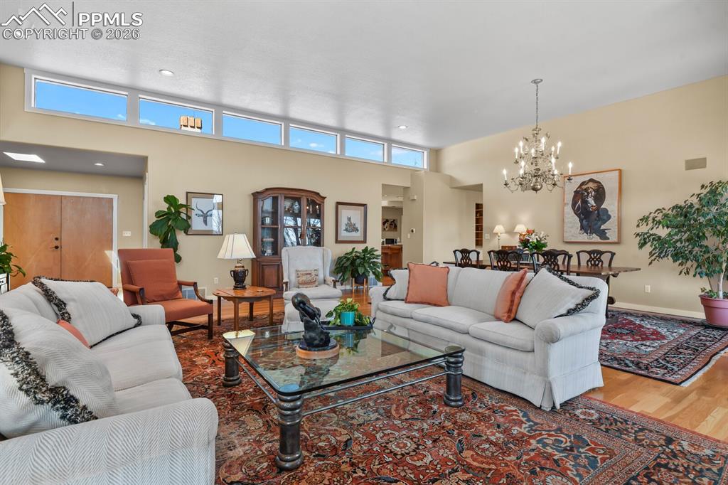 Another view of the Living Room with Dining Room, showing all the high windows, the chandelier and the hardwood floors.  Looking towards the front door.
