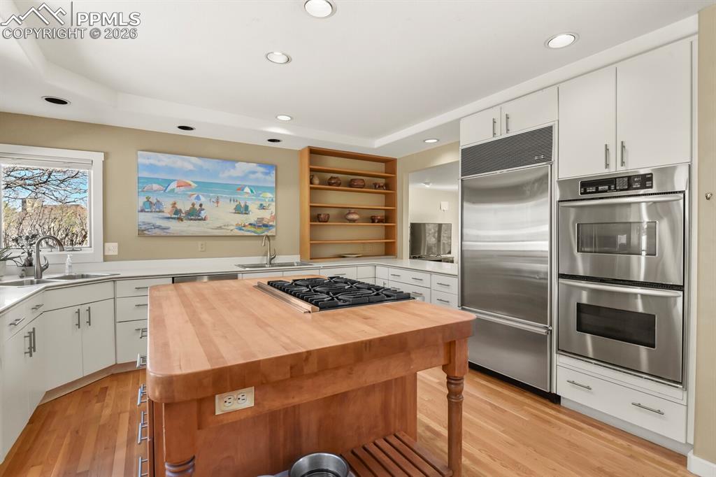 Kitchen featuring stainless steel appliances including double ovens and subzero refridgerator, white cabinets, open shelves, recessed lighting and windows.  Hutch open to the Dining Area.