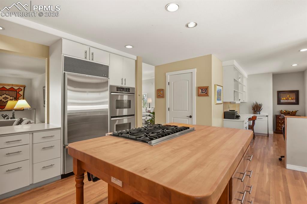 Kitchen with light wood-type flooring, stainless steel appliances, white cabinets, recessed lighting, and butcher block counters