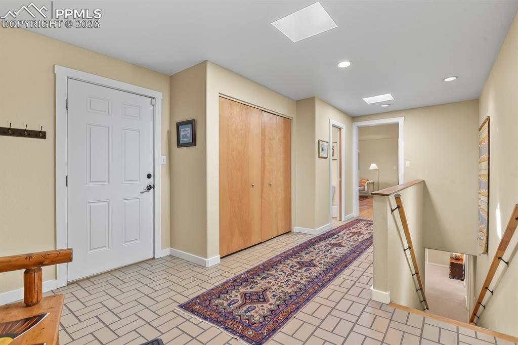 Mud Room area, skylights, tile floorings.  Door to the 3-car garage, double closet, door to one of two powder rooms on the main level.  One of two staircases down to the lower level.