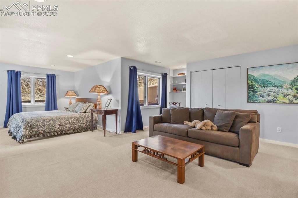 This is a second bedroom suite, with a sitting area, lots of windows, shelving and carpet.