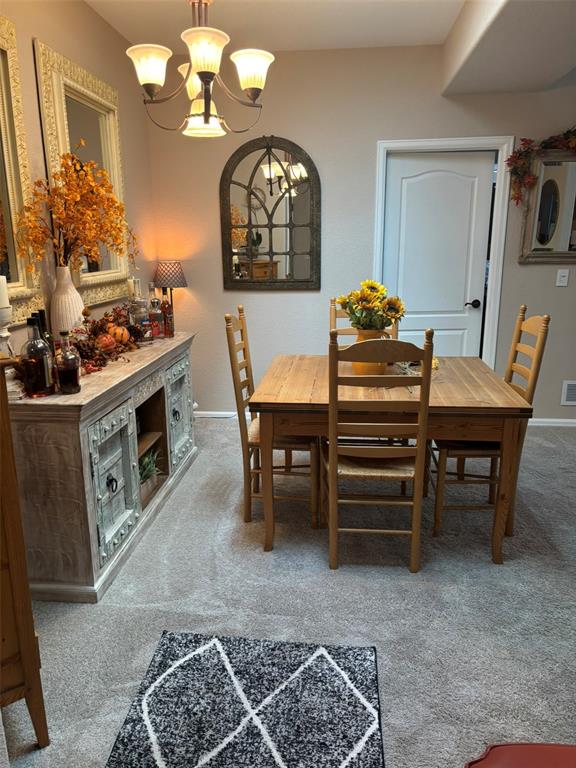 Dining space with light colored carpet and a chandelier