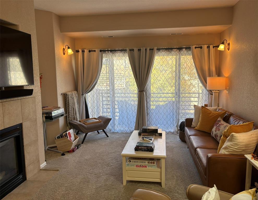 Living room featuring a textured wall, a fireplace, healthy amount of natural light, and light carpet
