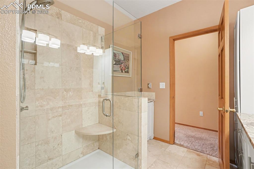 Full bath featuring a stall shower, vanity, and light tile patterned flooring