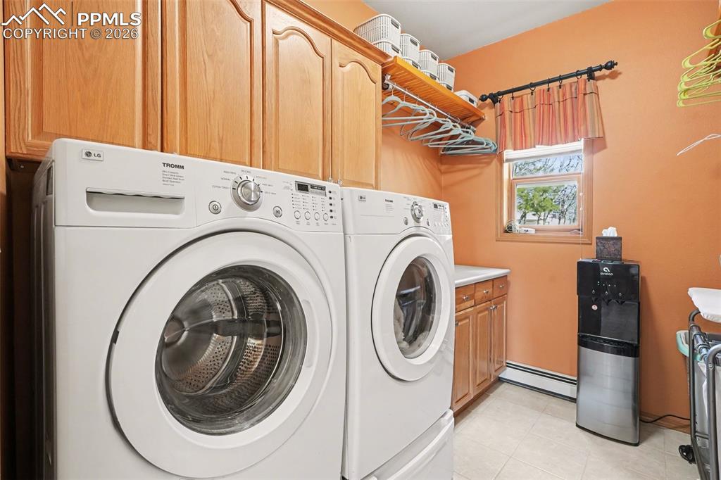 Laundry room with a baseboard heating unit, washer and dryer, and cabinet space