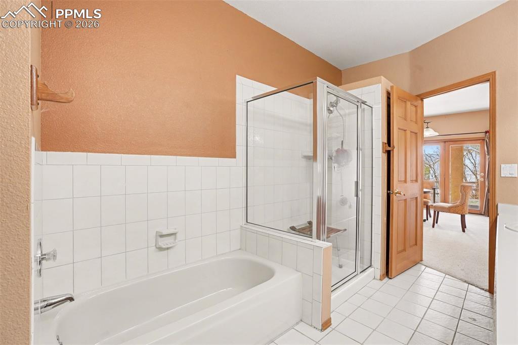 Full bathroom with a bath, a stall shower, light tile patterned flooring, and light colored carpet