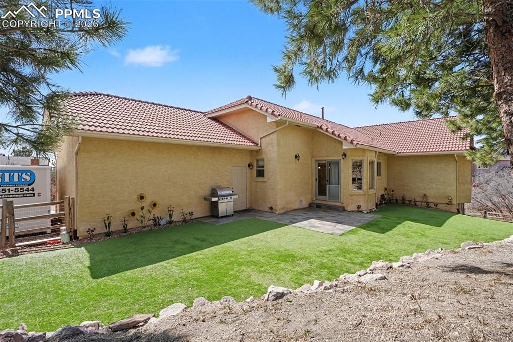 Rear view of property with stucco siding, a tile roof, and a patio area