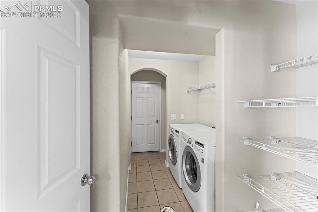 Washroom featuring light tile patterned floors, separate washer and dryer, and arched walkways