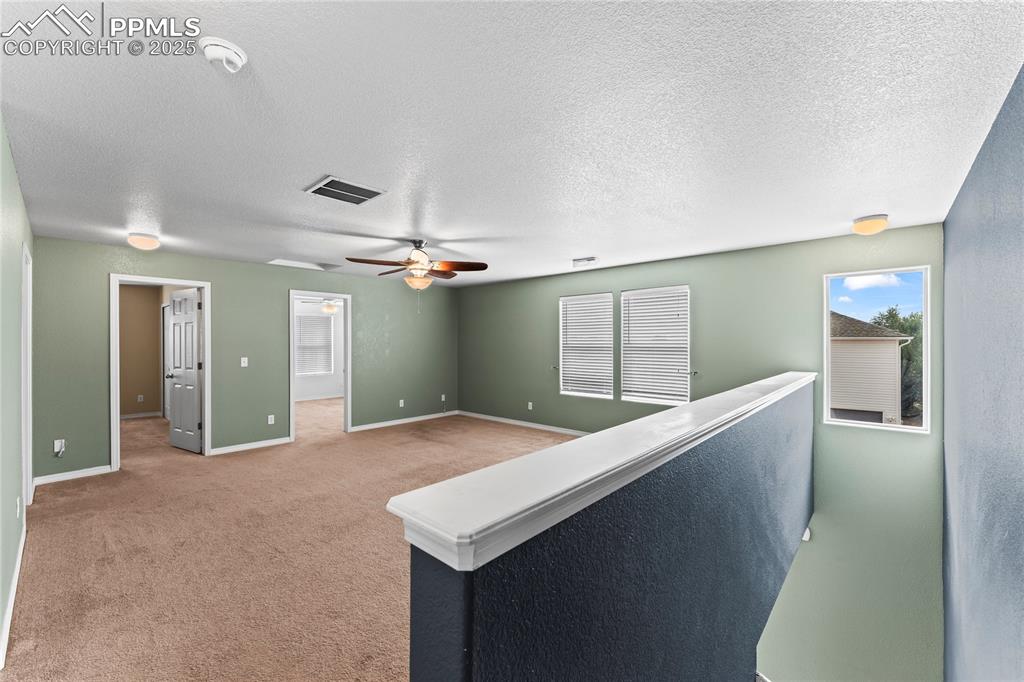 Corridor featuring a textured ceiling and light carpet