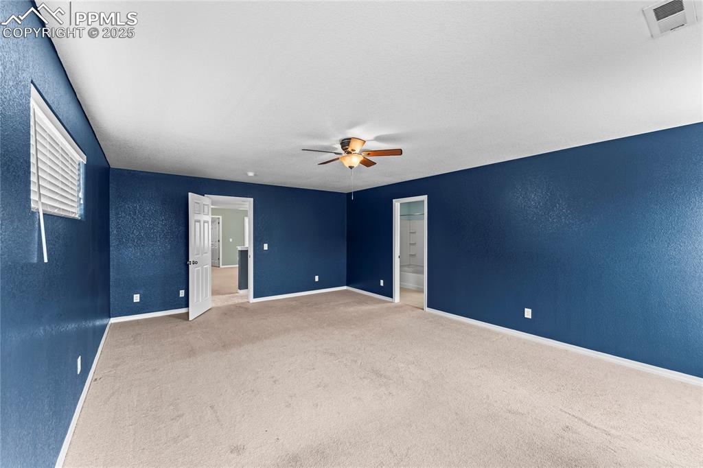 Carpeted spare room with a textured wall and a ceiling fan
