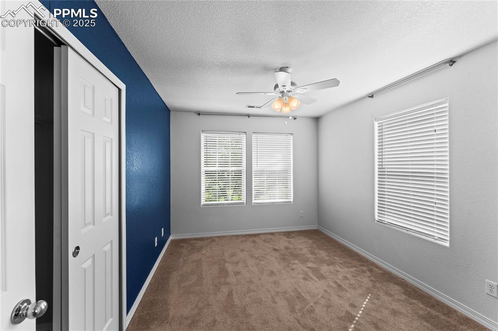 Spare room with a textured ceiling, carpet, ceiling fan, and a textured wall
