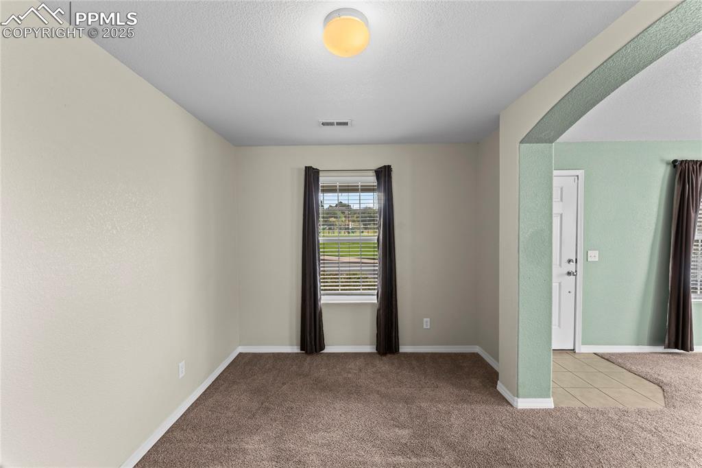 Carpeted spare room featuring a textured ceiling and baseboards
