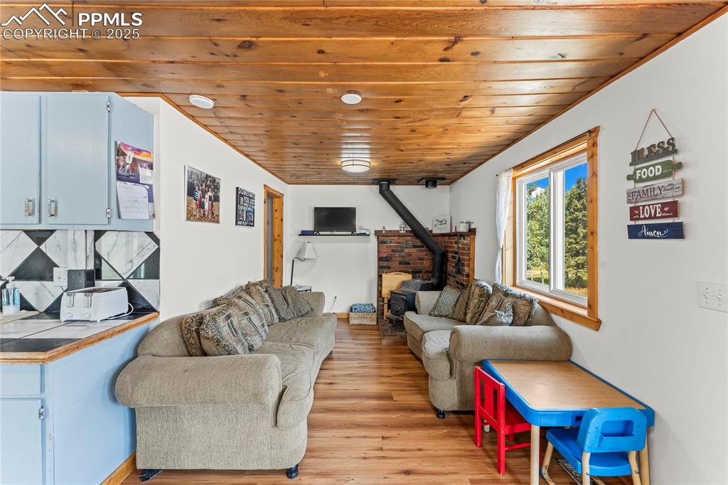 Living room with a wood stove, wooden ceiling, and light wood-style floors
