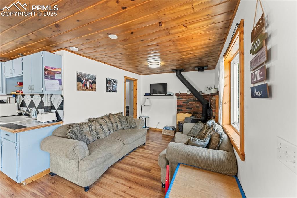 Living room featuring a wood stove, wood ceiling, and light wood-style floors
