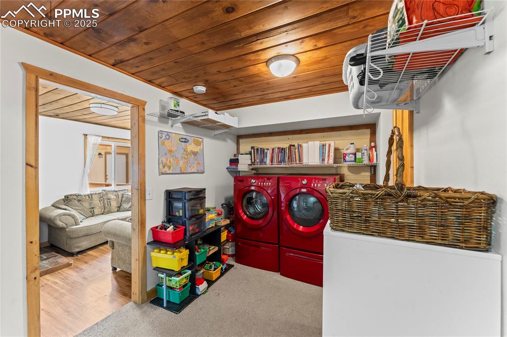 Laundry room featuring wood ceiling, washer and clothes dryer, and carpet floors