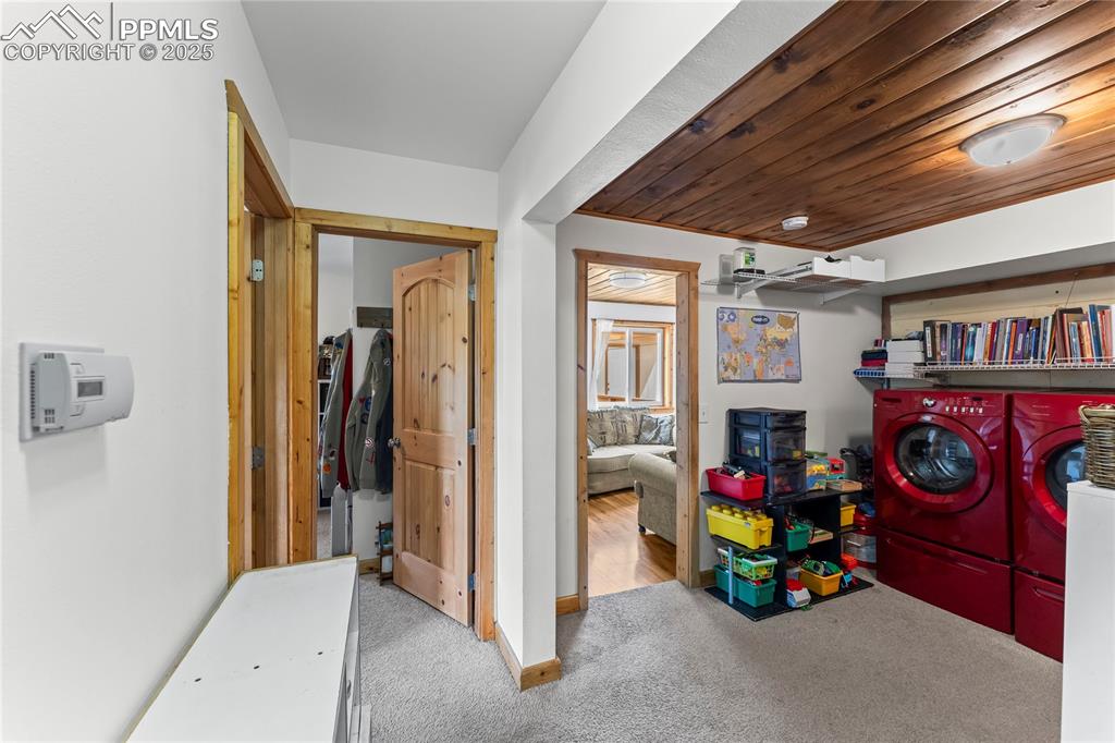 Laundry room featuring washing machine and dryer, carpet flooring, and wood ceiling