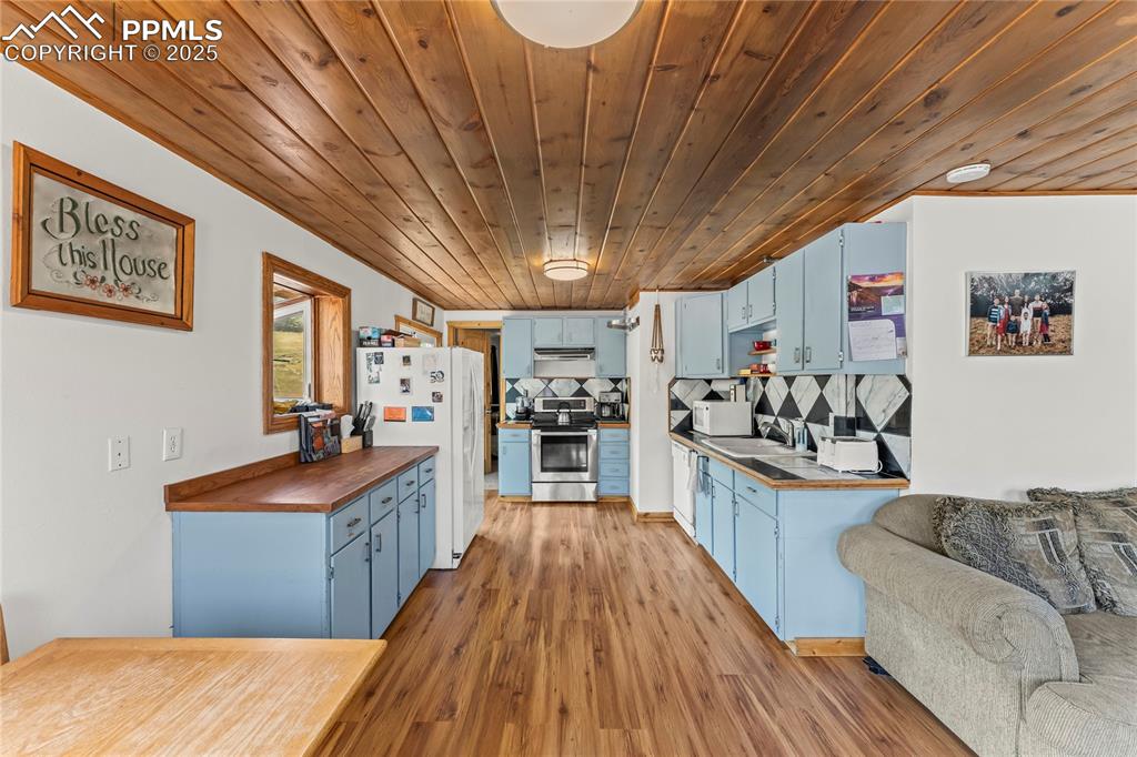 Kitchen with blue cabinets, appliances, light wood-style flooring