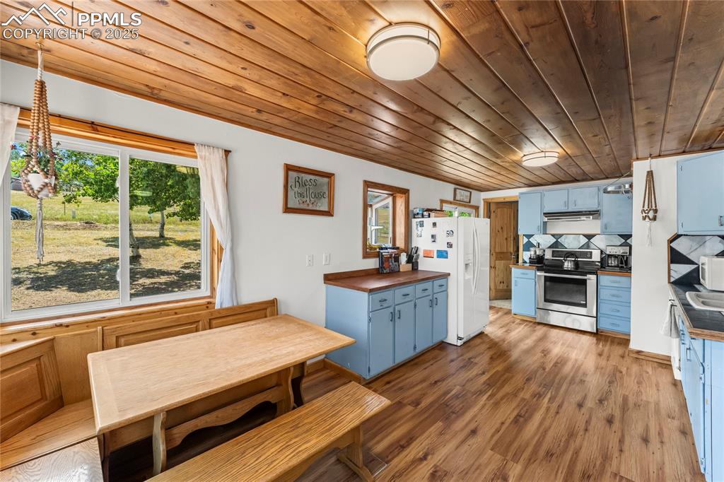 Kitchen with blue cabinets, appliances, light wood-style flooring