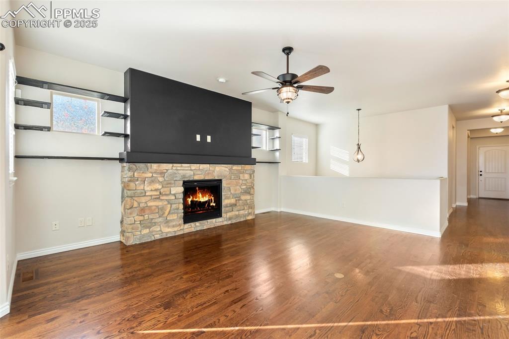Unfurnished living room with plenty of natural light, a fireplace, and dark wood-style flooring