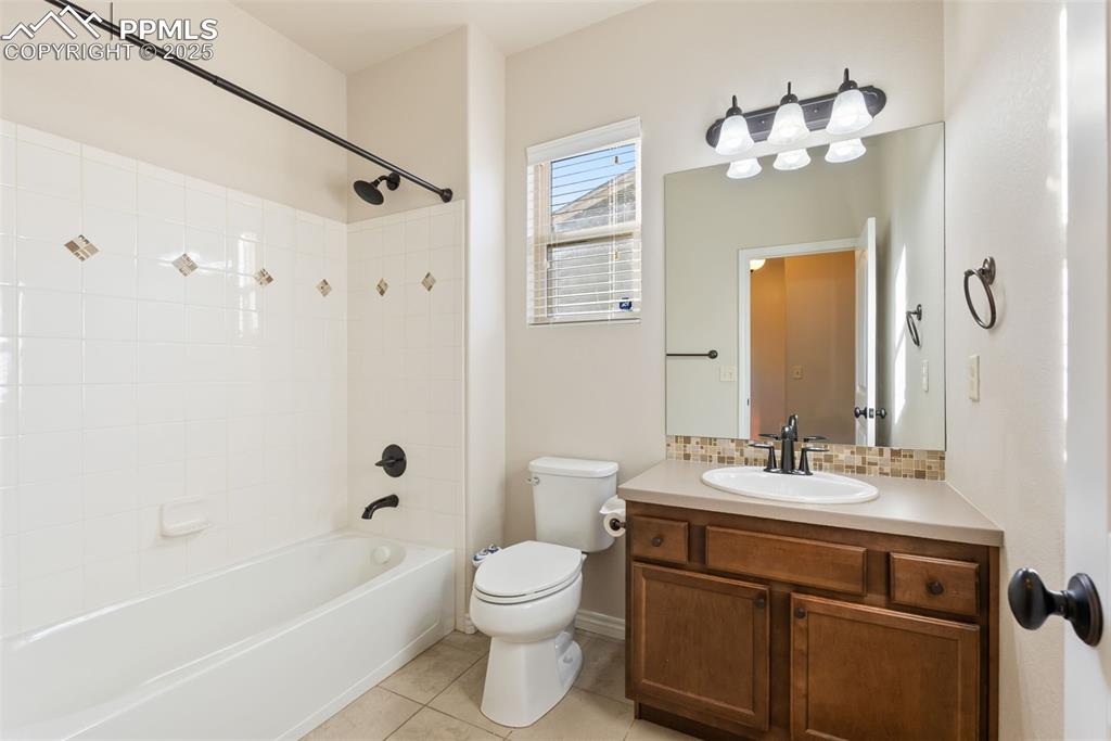 Full bath featuring shower / bathtub combination, vanity, light tile patterned floors, and backsplash