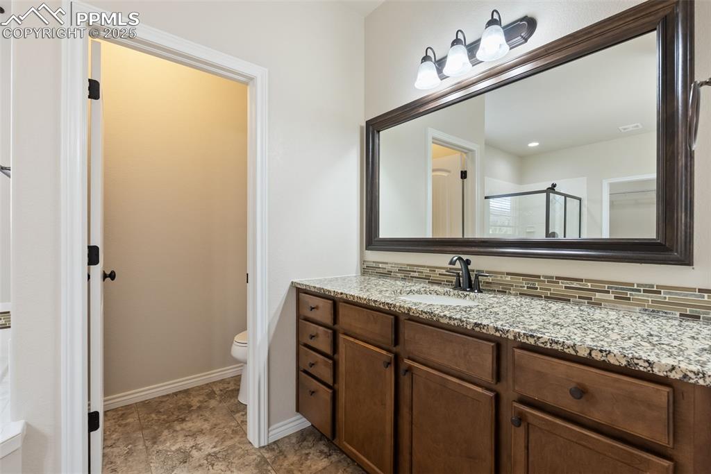 Bathroom with vanity, a stall shower, and decorative backsplash