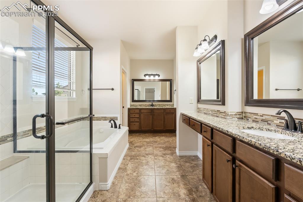 Full bathroom featuring two vanities, a garden tub, a shower stall, and tasteful backsplash