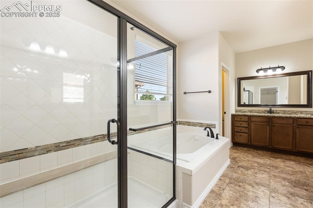 Bathroom featuring a bath, vanity, and a stall shower