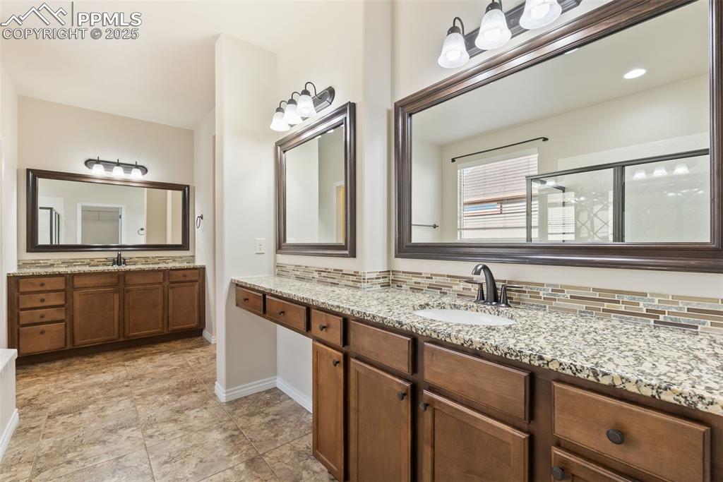 Bathroom with two vanities, a stall shower, and tasteful backsplash