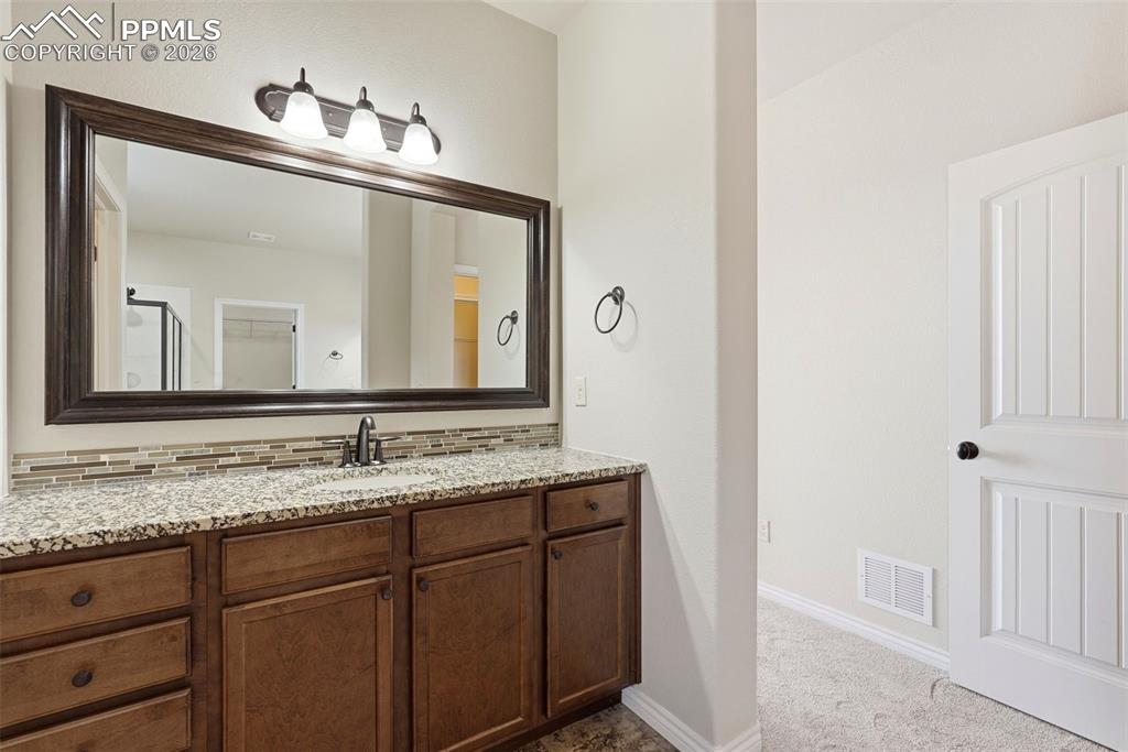 Full bathroom with vanity, decorative backsplash, and light carpet