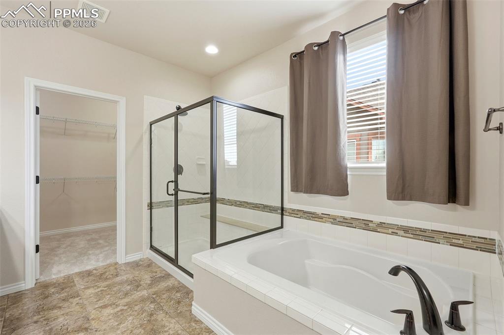 Full bath with a walk in closet, a garden tub, and a stall shower