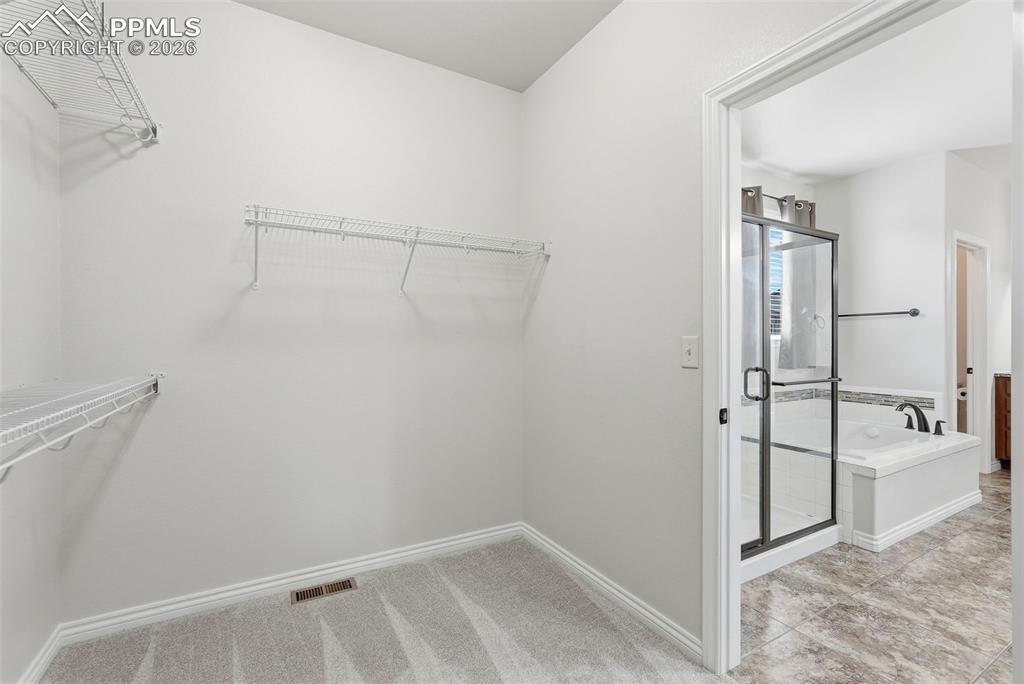 Walk in closet featuring light colored carpet