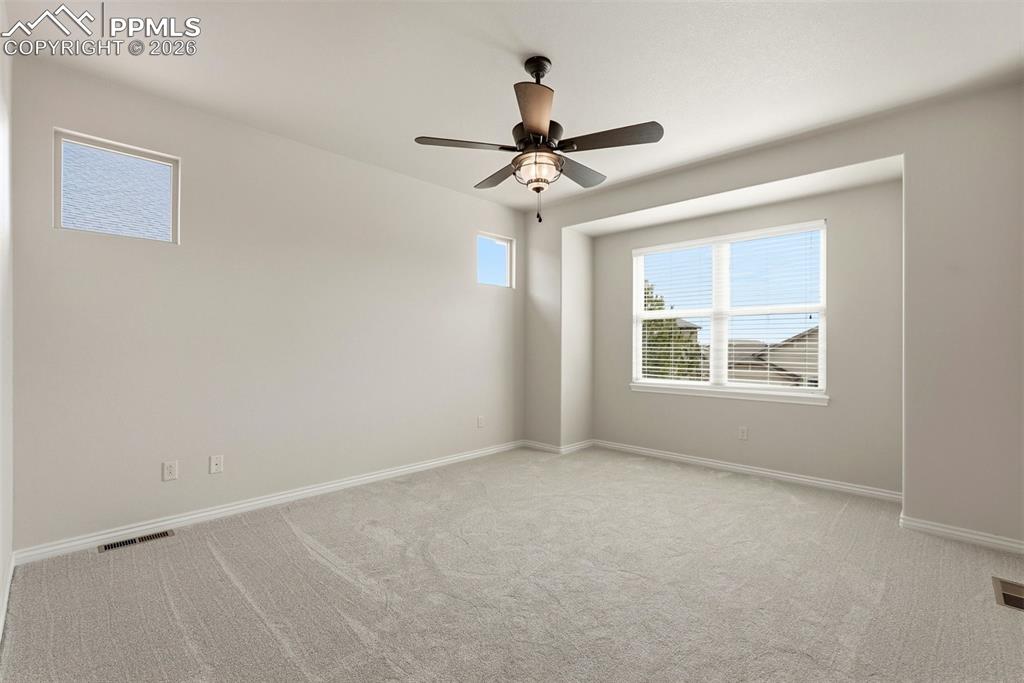 Empty room with light carpet and a ceiling fan