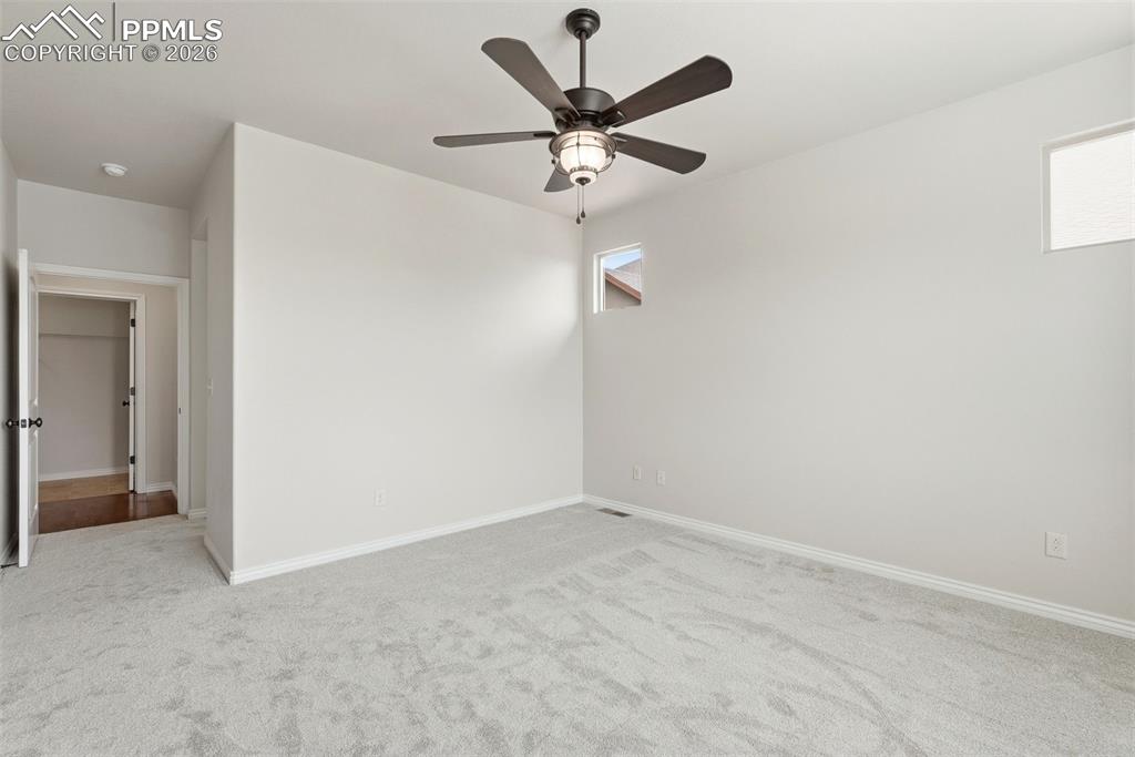Empty room with light colored carpet and a ceiling fan